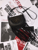 Black fringe handbag on a magazine with black and white text
